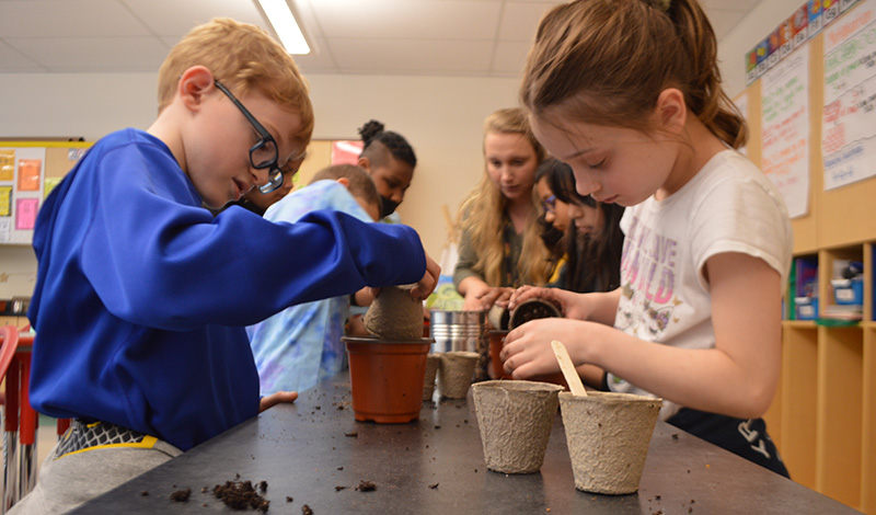 Students plant seeds in pots in classroom